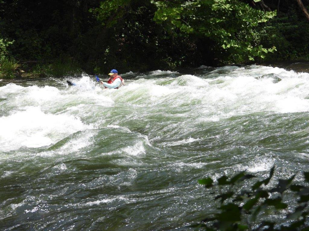 Kayaker in whitewater wave train